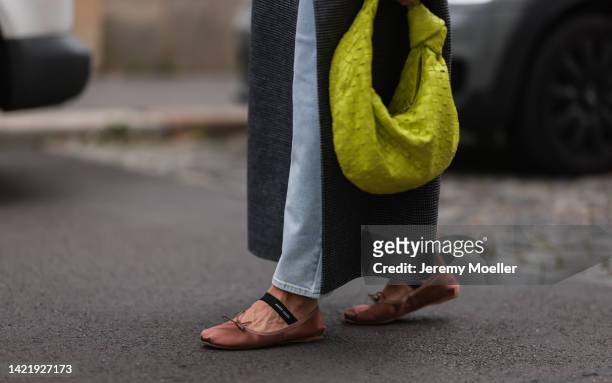 Sonia Lyson is seen wearing grey long wool coat from Ivy & Oak, Ivy & Oak light blue denim jeans, Miu Miu brown leather ballet flats and green acid...