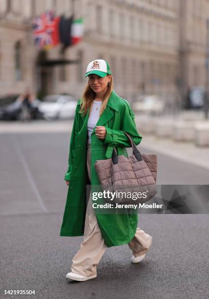 Sonia Lyson is seen wearing white Urban Outfitters cap, white Zara top, green Ducie London leather long coat, The Frankie Shop beige pants, Vee...