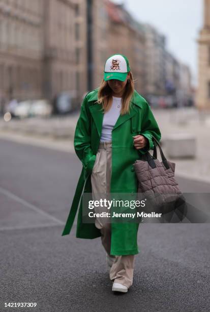 Sonia Lyson is seen wearing white Urban Outfitters cap, white Zara top, green Ducie London leather long coat, The Frankie Shop beige pants, Vee...