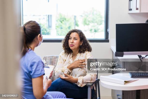 adult female patient talks with nurse - urgent care stock pictures, royalty-free photos & images