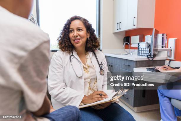 empathetic female doctor listens to unrecognizable boy - primary care stock pictures, royalty-free photos & images