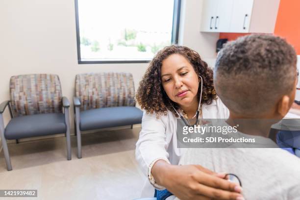unrecognizable boy sits quietly while doctor listens to his lungs - human lung stock pictures, royalty-free photos & images