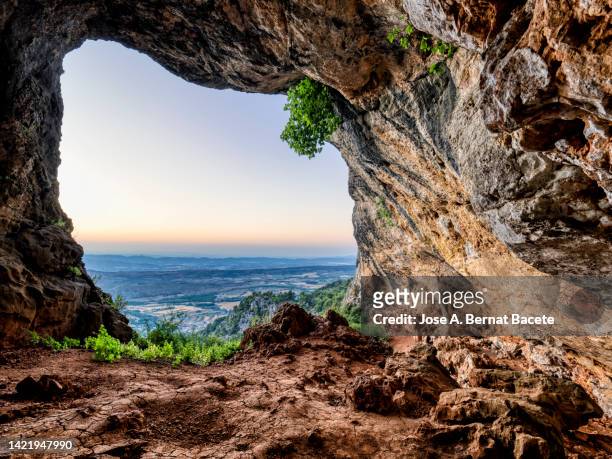 landscape from inside a large cave in the mountains at sunset. - light at the end of the tunnel stock pictures, royalty-free photos & images
