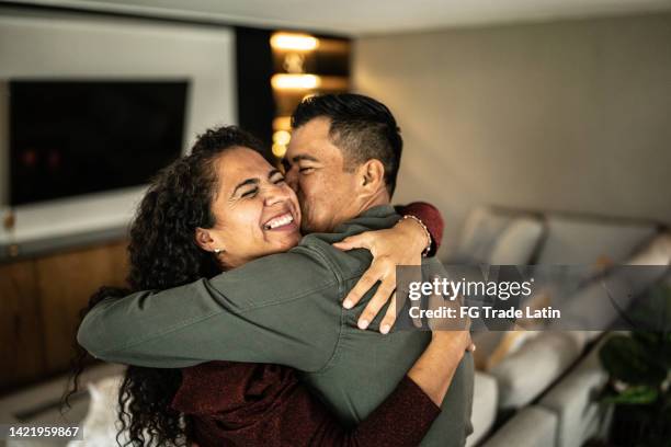 mid adult couple embracing in the living room at home - arriving home stockfoto's en -beelden