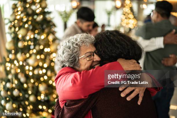 donna anziana che abbraccia la sua figlia sul natale a casa - frase breve foto e immagini stock