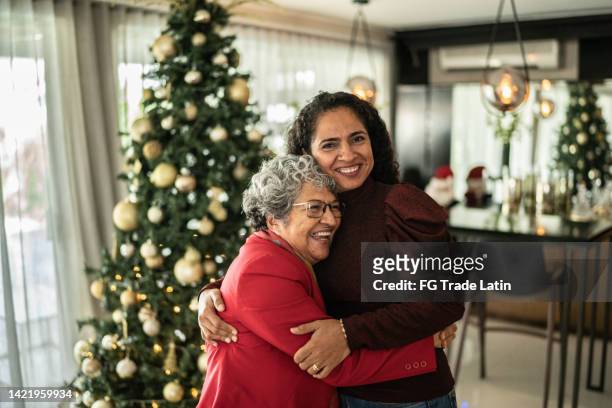 portrait of mother and daughter hugging on christmas at home - mexican christmas stock pictures, royalty-free photos & images
