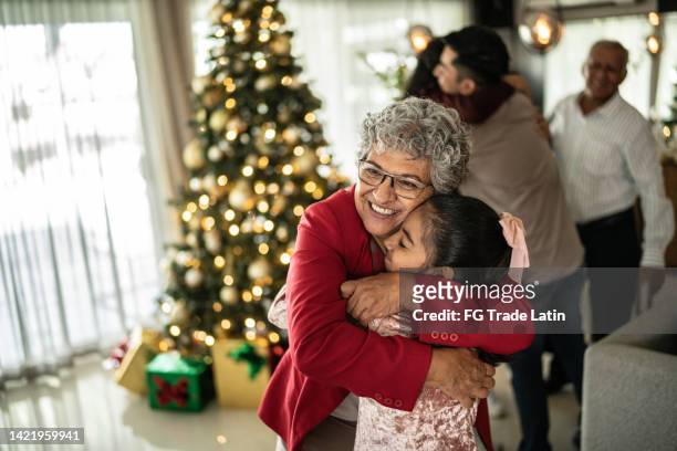 großmutter umarmt ihre enkelin an weihnachten zu hause - lateinamerikaner oder hispanic stock-fotos und bilder