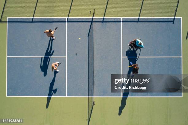 adultos jóvenes jugando pickleball en una cancha pública - tenista fotografías e imágenes de stock