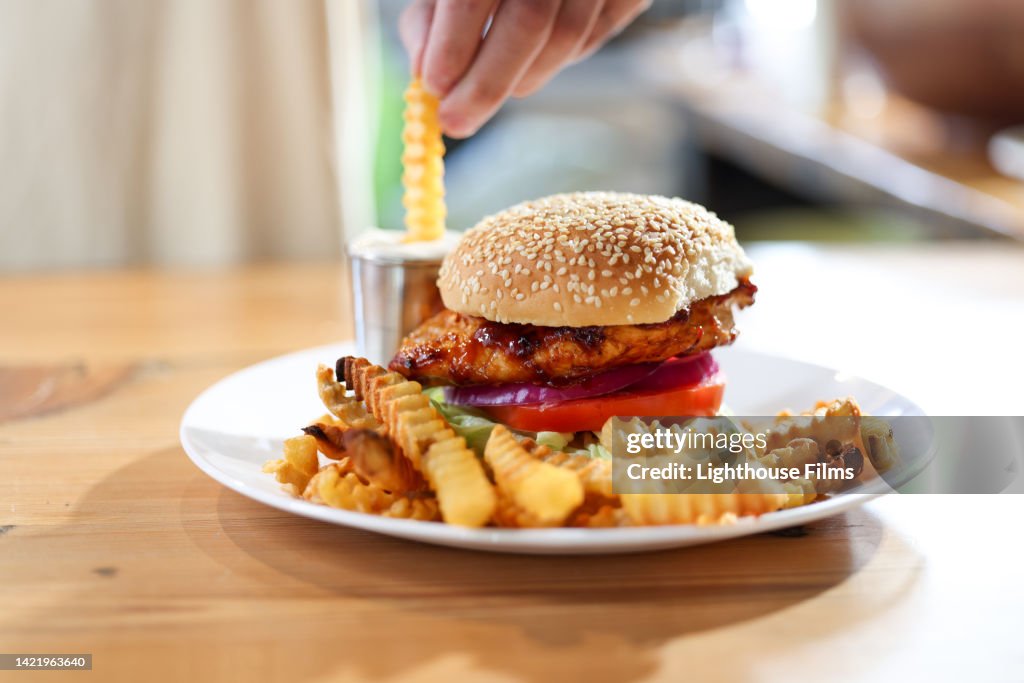 CU adult dips french fry into sauce next to delicious burger