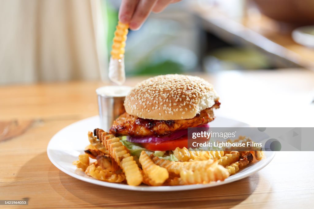 CU adult dips french fry into ranch dressing alongside burger