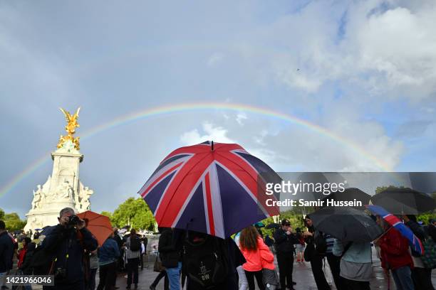 Man looks on holding a Union flag umbrella as a rainbow is seen outside of Buckingham Palace on September 08, 2022 in London, England. Buckingham...