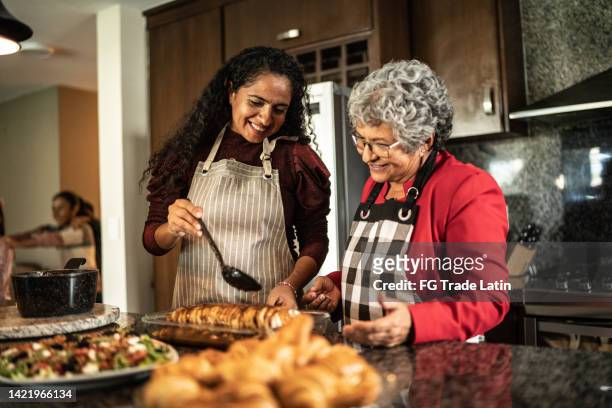 mãe e filha preparando comida no balcão da cozinha em casa - assado prato principal - fotografias e filmes do acervo