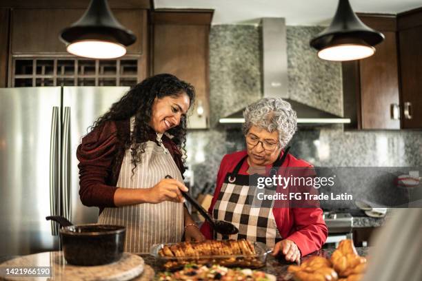 mutter und tochter bereiten zu hause in der küchentheke essen zu - pinafore kleid stock-fotos und bilder