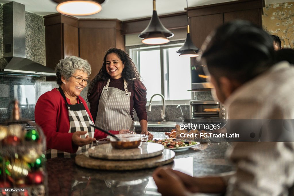 Mother and daughter preparing food for family at kitchen at home