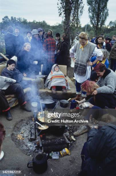 Women at the Greenham Common Women's Peace Camp around a camp fire at RAF Greenham Common, Berkshire, UK, circa 1983. The camp was set up by women...