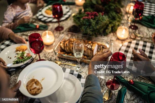 man putting loin with fruit on plate in the dinner table on christmas at home - mexican christmas stock pictures, royalty-free photos & images