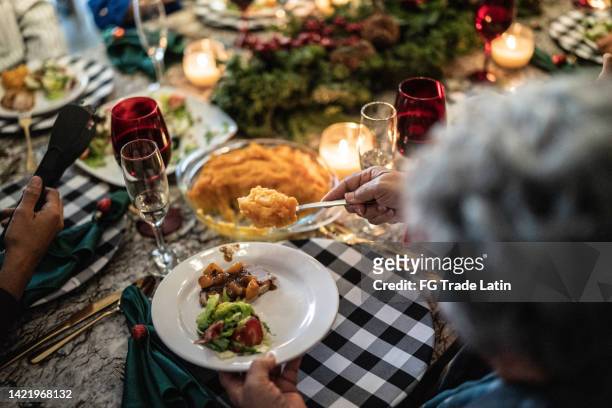 donna anziana che mette la purea sul piatto a tavola a natale a casa - piatto di portata foto e immagini stock