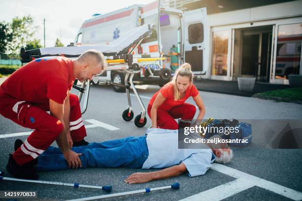 paramedics providing first aid to older man  injured  in accident - victim services stock pictures, royalty-free photos & images