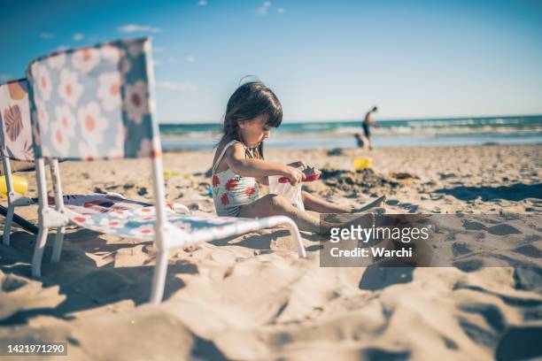 little girl playing with sand by the beach - sand pail and shovel stock pictures, royalty-free photos & images