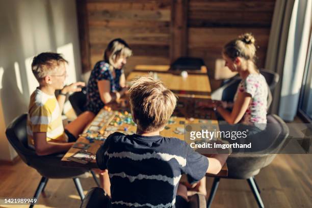 familia jugando un gran juego de mesa moderno juntos en casa - game night leisure activity fotografías e imágenes de stock