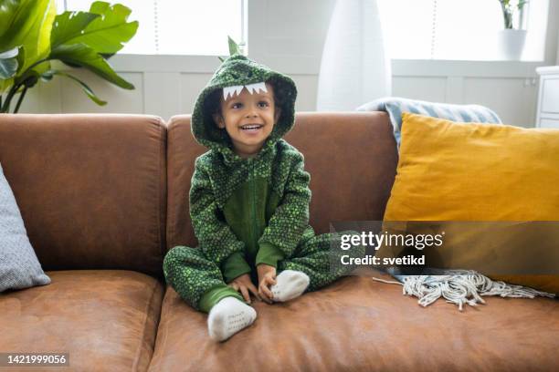 pequeño dinosaurio en el sofá - disfraz fotografías e imágenes de stock