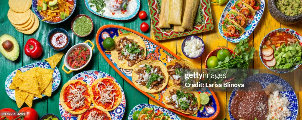 Mexican festive food for independence day independencia - chiles en nogada, tacos al pastor, chalupas pozole, tamales, chicken with mole poblano sauce. Colorful background, top view