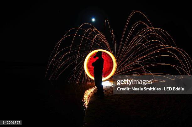 man spinning fire sticks - frensham stock pictures, royalty-free photos & images