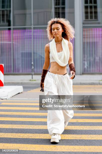 Influencer Michele Winchester, wearing white pants by Emmiol, a white shirt with a wide scarf by Emmiol, brown arm cuffs by Emmiol and white shoes by...