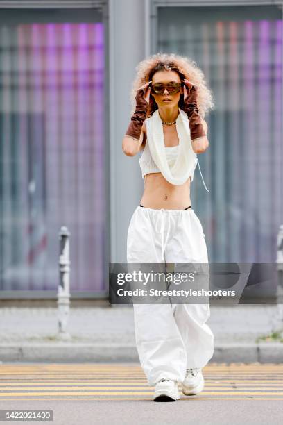 Influencer Michele Winchester, wearing white pants by Emmiol, a white shirt with a wide scarf by Emmiol, brown arm cuffs by Emmiol, white shoes by...
