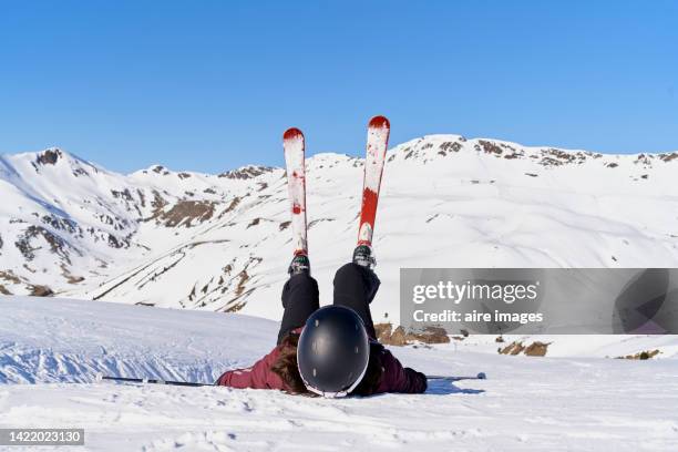 beginner skier lying on the snow after a fall while skiing, practicing to improve her skills during her winter vacation, beautiful blue sky in the background. - looking down photos et images de collection