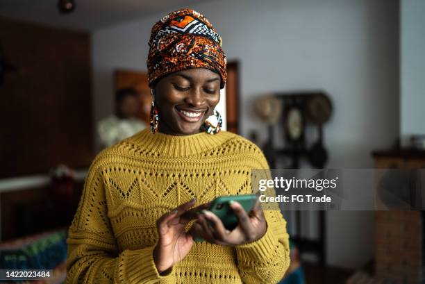 young woman using the mobile phone at home - african woman stockfoto's en -beelden