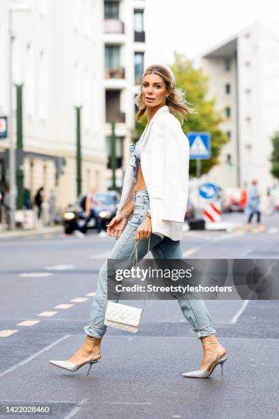 Model Annika Gassner, wearing a Jeans by Pepe, a blue short bustier with a loop by Cider, a white blazer by Zara, white pumps by Zara and a white bag...