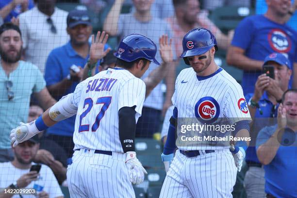 Seiya Suzuki of the Chicago Cubs celebrates with Ian Happ after hitting a solo home run against the Cincinnati Reds during the eighth inning at...