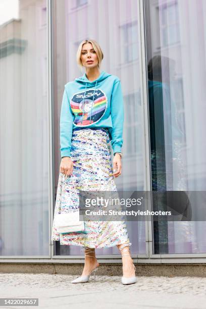 Model Annika Gassner, waering a blue hodie with a snoopy print by Dawid Tomaszewski, a multicolored glitter scirt, white pumps by Zara and a white...
