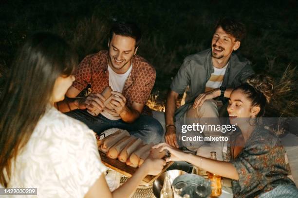 friends enjoying hot dogs while camping outdoors - double date stock pictures, royalty-free photos & images