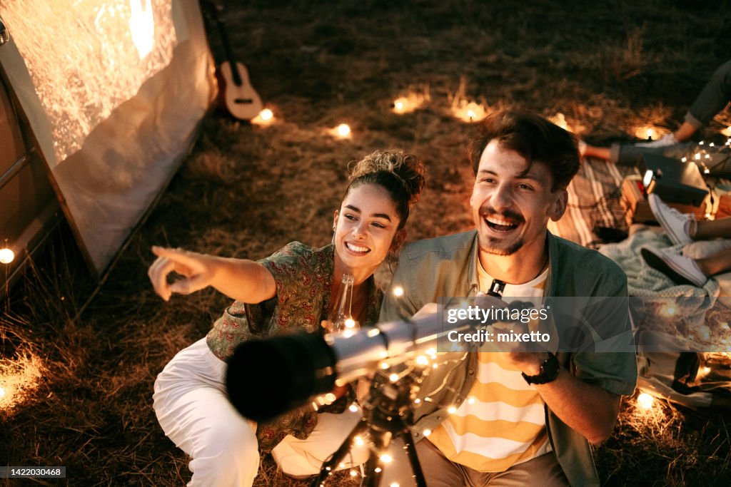 Couple stargazing together with a astronomical telescope