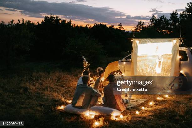 group of friends enjoying movie night outdoors in nature - projectieapparatuur stockfoto's en -beelden