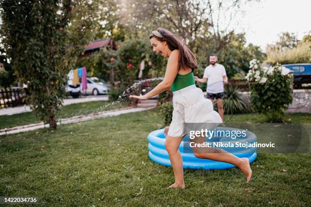 spraying with a hose in the yard - mom flirting stockfoto's en -beelden