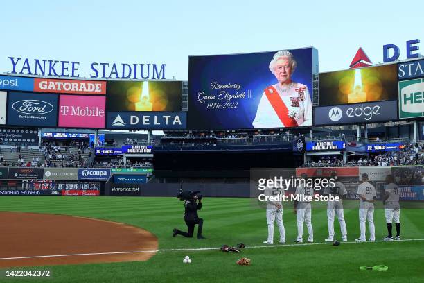 Members of the New York Yankees stand during a moment of silence in honor of Queen Elizabeth II prior to the game against the Minnesota Twins at...