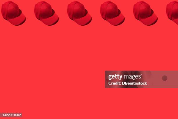 pattern of red baseball caps, on top, on red background. concept of fashion, clothing, accessories, hip hop, baseball, sport, uniform and sun protection. - style studio day 1 stockfoto's en -beelden