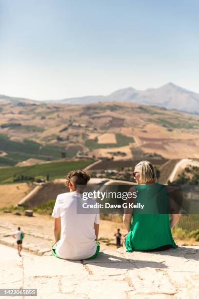 rear view of mother and teenage son sitting overlooking valley - single mother teen stock pictures, royalty-free photos & images