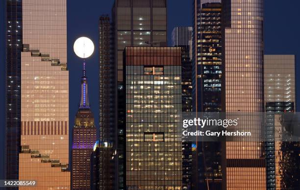 The moon rises behind the Empire State Building in New York City lit in purple to honor the life of Queen Elizabeth II who passed away earlier in the...