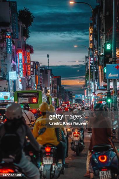 rush hour, busy traffic jam during sunset and colorful perspective of hai ba trung st with numerous hotel, bar and shop sign boards, crowded with people, motorbikes - ho chi minh city stockfoto's en -beelden