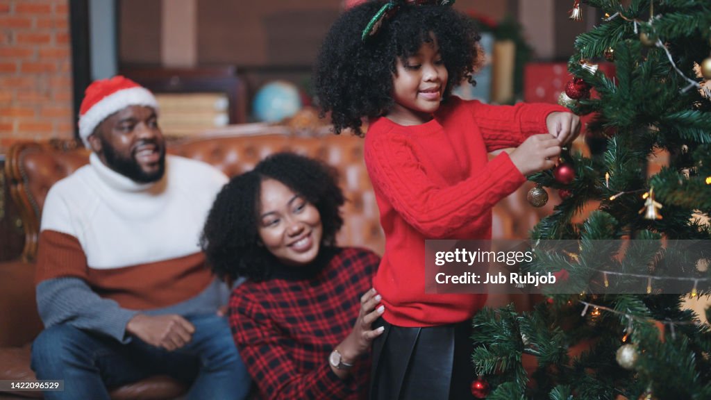 Father, mother and child family rejoicing in the joy of opening a gift box on Christmas Day.