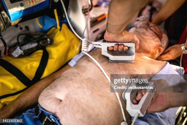 medical urgency in the ambulance .emergency doctor using defibrillator - defibrillator bildbanksfoton och bilder