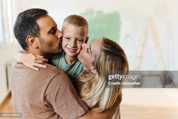 loving parents kissing their small son during home renovation process. - friends kissing cheeks stockfoto's en -beelden