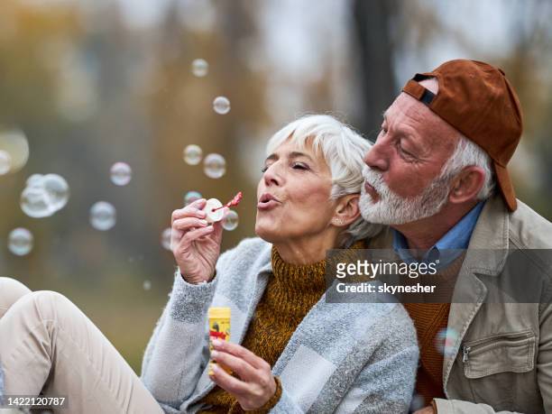 happy senior couple blowing bubbles in nature. - bubbles happy stockfoto's en -beelden