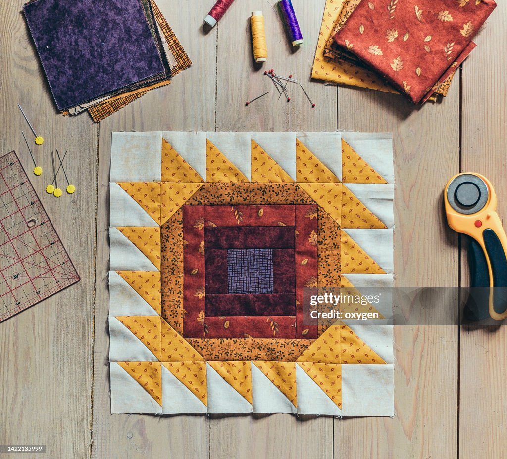 Quilting Sewing Accessories, Patchwork Sunflower Summer Autumn Block Fragment of Quilt. Patchwork Red Yellow Block Quilt, Sewing Accessories, on Wooden Background