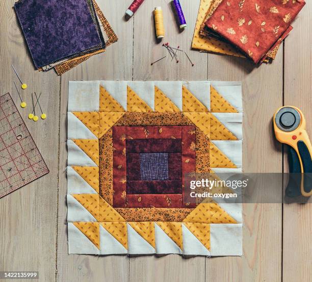 quilting sewing accessories, patchwork sunflower summer autumn block fragment of quilt. patchwork red yellow block quilt, sewing accessories, on wooden background - patchwork stock pictures, royalty-free photos & images