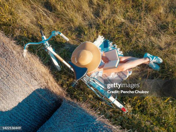 top view of woman with old style bicycle reading book while sitting on lawn - reading glasses top view stock pictures, royalty-free photos & images